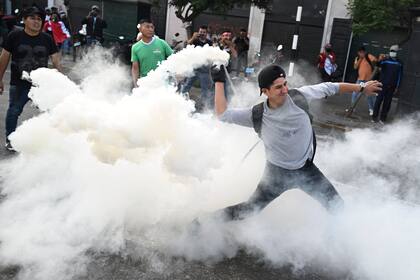 Un partidario del ex presidente peruano Pedro Castillo lanza un bote de gas lacrimógeno a la policía antidisturbios durante una protesta cerca del Congreso en Lima el 12 de diciembre de 2022. 