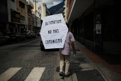 Un partidario del líder opositor de la Asamblea Nacional, Juan Guaidó, camina con un cartel que dice: "Ultimatum, no más comunismo" después de asistir a misa en una iglesia con Guaidó en Caracas