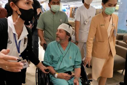 Un pasajero australiano, en el centro, que resultó herido en un vuelo afectado por turbulencias, habla con periodistas en el hospital Samitivej Srinakarin en Bangkok, Tailandia, el jueves 23 de mayo de 2024. El vuelo SQ321 iba desde el aeropuerto londinense de Heathrow a Singapur cuando encontró fuertes turbulencias el martes.