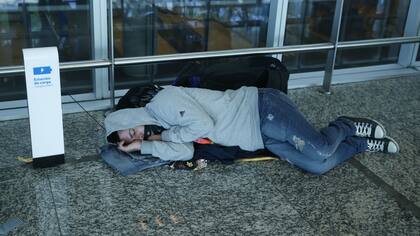 Un pasajero duerme incómodo en el suelo
