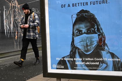 Un peatón pasa junto a un cartel de la organización benéfica Unicef, que promociona las vacunas contra el Covid-19, en Manchester, noroeste de Inglaterra, el 5 de enero de 2021