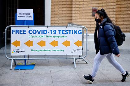 Un peatón que se cubre la cara pasa junto a un letrero que dirige a las personas a un centro de pruebas de Covid-19 en la estación de tren London Bridge en el centro de Londres el 5 de abril de 2021
