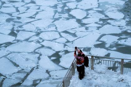 Un peatón se detiene para sacar una foto del río Chicago. El fenómeno del frío extremo, llamado vórtice polar, ha descendido en gran parte del centro y el este de los Estados Unidos, en Chicago.