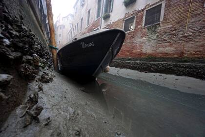 Un pequeño bote yace en el fondo de un canal interno durante una marea baja en Venecia, Italia, el 17 de febrero de 2023. Venecia ha estado luchando durante muchos días con una marea baja, que es empezando a crear serios problemas también para la navegabilidad.