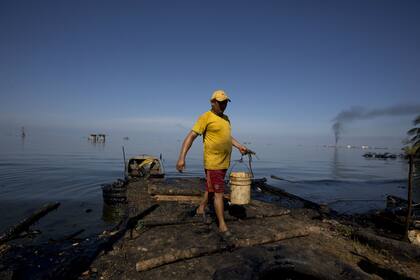 Un pescador recoge agua contaminada con petróleo en el Lago Maracaibo