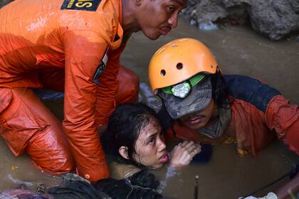 Los bomberos rescatan a una joven de 15 años que quedó atrapada en los escombros de su casa luego del terremoto y posterior tsunami