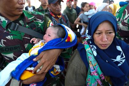 Un soldado asiste a un bebé y a su madre luego de que fueran afectados por el terremotos y posterior tsunami