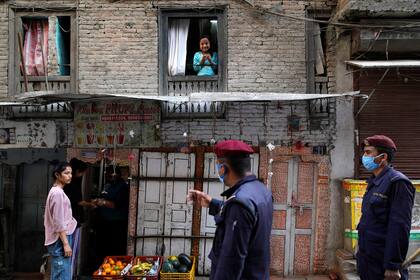 Un policía alerta a una mujer por no llevar barbijo durante la cuarentena, en Nepal