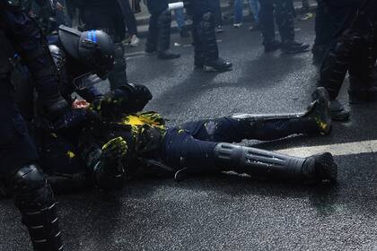 Un policía antidisturbios yace en la calle durante una manifestación, el lunes 1 de mayo de 2023 en París.