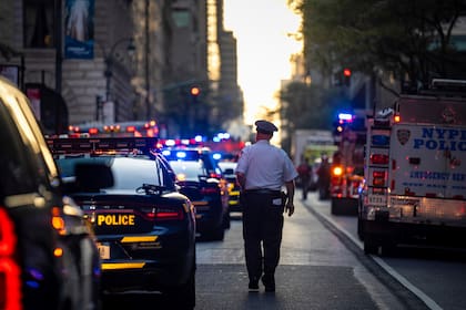 Un policía camina entre vehículos policiales en la calle 52, frente a un edificio de oficinas de Manhattan en el que hubo un tiroteo, el lunes 28 de julio de 2025, en Nueva York. (AP Foto/Angelina Katsanis)