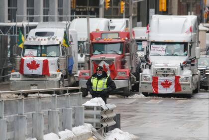 Un policía de pie frente a camiones que bloquean el paso hacia las calles del centro como parte de una protesta contra las medidas impuestas por el COVID-19, el miércoles 9 de febrero de 2022, en Ottawa. (Patrick Doyle/The Canadian Press vía AP)