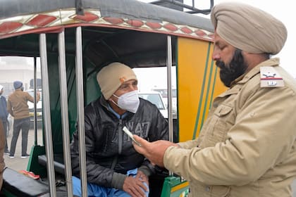 Un policía de Punjab revisa el pasaporte de un ciudadano paquistaní, que anteriormente estaba varado en la India tras el cierre de fronteras para frenar la propagación del coronavirus