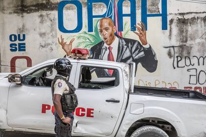Un policía frente a un mural de Moise, en Puerto Príncipe