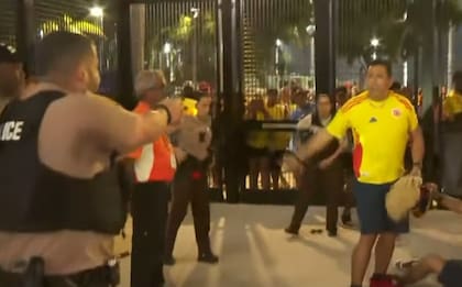 Un policía le apunta una pistola Taser a un hincha colombiano antes de dispararle