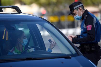 Un policía local revisa la identificación de un conductor en un control de tráfico, para controlar el movimiento de personas en Madrid, el 3 de octubre de 2020