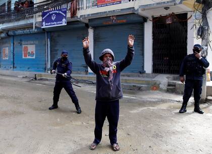 Un policía mantiene la distancia con un detenido con una vara