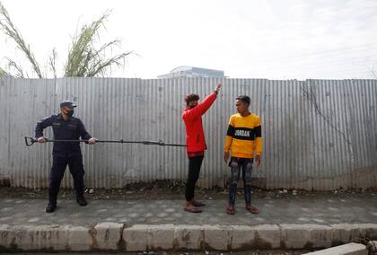 Un policía lleva a dos jóvenes que violaron la cuarentena