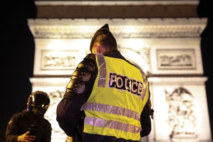 Un policía patrulla bajo el Arco del Triunfo durante la víspera de Año Nuevo cuando se implementa el toque de queda de 20 a 6 en Francia para evitar una tercera ola de infecciones por Covid-19, en París, el 31 de diciembre de 2020