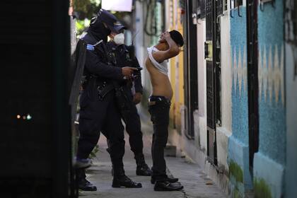 Un policía registra y comprueba la documentación de un hombre que vive en la comunidad Kiwanis, en un patrullaje preventivo en busca de miembros de pandillas en Soyapango, El Salvador, el 16 de agosto de 2022 durante el estado de excepción.