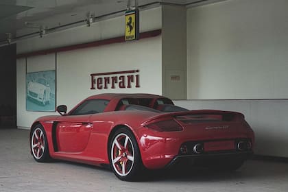 Desde atrás, el Porsche Carrera GT debajo de un cartel de la firma italiana Ferrari