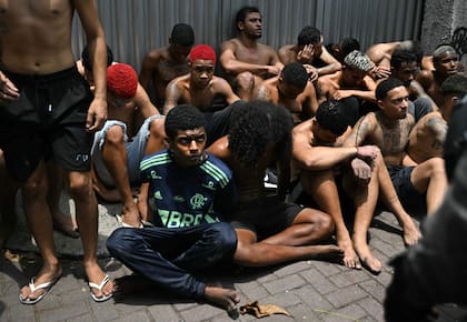 Un presunto delincuente arrestado durante la Operación Contención en la favela Vila Cruzeiro mira fijamente a un policía en el complejo Penha, Río de Janeiro