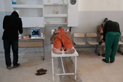 Un prisionero extranjero yace sobre una mesa de examen junto a un médico dentro de una prisión en Hasaka