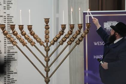 Un rabino enciende nuevamente las velas de una menorá después de un incidente en el que un legislador de extrema derecha apagó las velas, en Varsovia, Polonia, el martes 12 de diciembre de 2023.