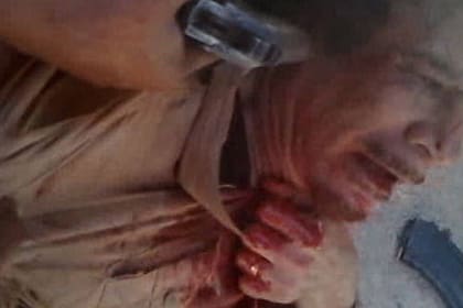 Un rebelde apoya un arma en la sien de un Muammar Khadafy ya vencido