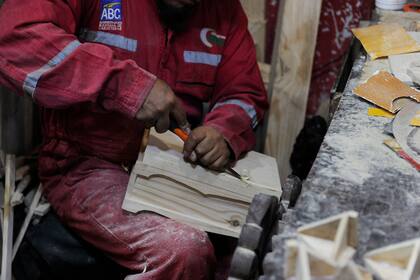 Un recluso del penal de San Pedro trabaja con madera para elaborar artesanías que serán vendidas en la feria Alasita, de La Paz
