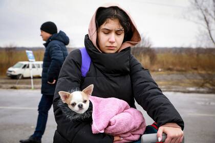 Un refugiado que huye de la guerra en Ucrania. carga un perro después de cruzar la frontera en Palanca, Moldavia