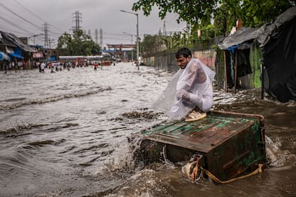 Un residente de Bombay se refugia en un contenedor de basura de las lluvias del monzón.