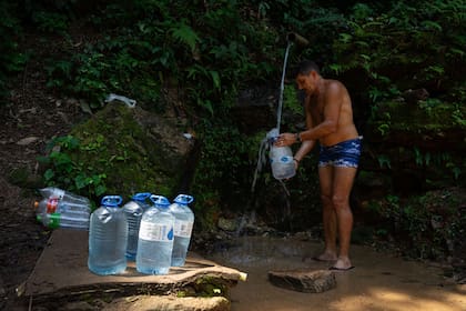 Un residente de la Rocinha recolecta agua de una pesqueña cascada, en medio de la ola de calor extremo en Río de Janeiro