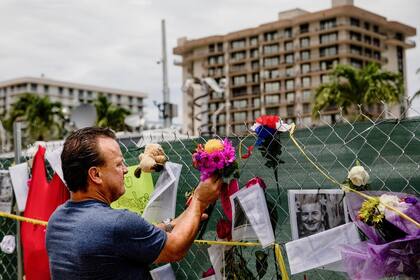 Un residente de Surfside pone flores en un memorial improvisado a las víctimas del derrumbe 