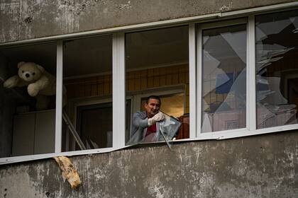 Un residente retira los trozos de las ventanas rotas en un apartamento tras un ataque con misiles en Dnipro el 10 de octubre de 2022, en medio de la invasión rusa de Ucrania. 