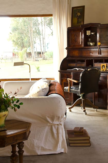 Un rincón del living con muebles cargados de tradición, pero aligerados por las paredes y las fundas blancas.