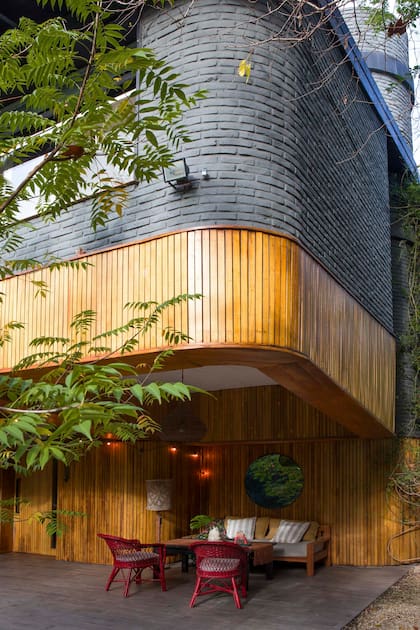 Un rincón encantador hecho, sobre todo, con ingenio: reúne una lámpara de pie vintage, sillas Mar del Plata pintadas de rojo y un espejo circular que refleja el verde.