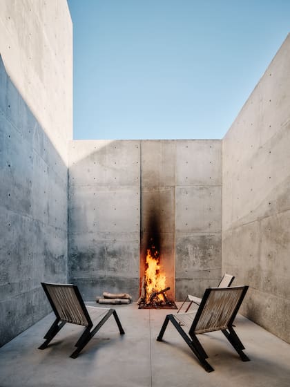 Un rincón minimalista donde el fuego se convierte en protagonista y el concreto abraza la calma del desierto.