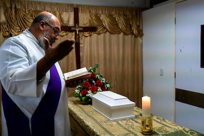 Un sacerdote católico oficia una misa durante el velorio del hijo de Wendy Dulcey, quien falleció un mes después de nacer en la unidad de cuidados intensivos del hospital Universitario de Caracas el 11 de enero de 2021