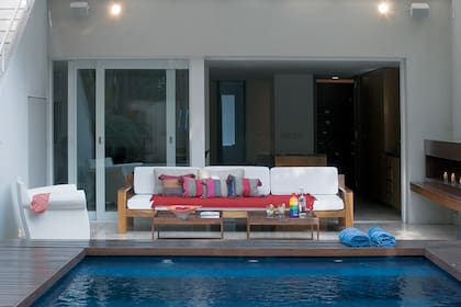 Un sillón de tres cuerpos de madera de incienso con asientos tapizados en algodón y almohadones realizados con aguayos y dos mesas bajas de lapacho visten este espacio que, gracias al hogar ubicado en un lateral, puede disfrutarse también cuando hace frío