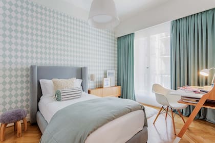 Un singular empapelado marca el tono en el cuarto de una adolescente. La paleta conformada por verde acqua, celeste, blanco y las cortinas de terciopelo funcionan a la perfección con la madera.