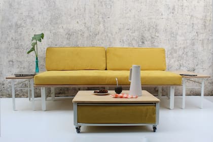 Un sistema compuesto por un sofá de dos cuerpos, dos mesas de arrime, que también se utilizan como bancos, y una mesa ratona auxiliar que se convierte en apoyapies. La estructura general está pintada al horno. La madera utilizada es multilaminado, con terminación en hidrolaca satinada. El tapizado es en espuma de alta densidad y el textil tiene tratamiento antimanchas.