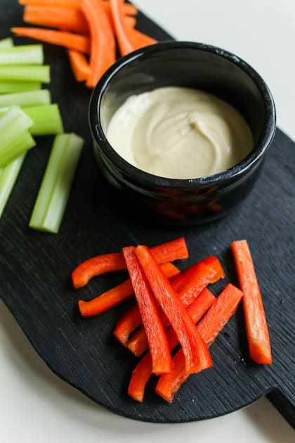 Un snack de hummus con bastones de zanahoria ofrece fibra y antioxidantes que benefician la salud intestinal y cardiovascular