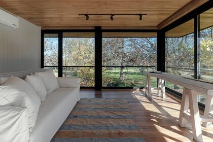 Un sofá y un tablón de madera: nada más necesita este espacio, en el que sobra con acostarse a contemplar el frondoso arbolado.