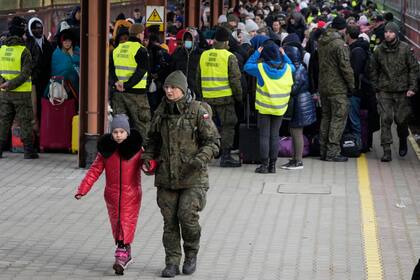 Un soldado acompaña a un niño mientras refugiados de Ucrania llegan a una estación de tren a Polonia