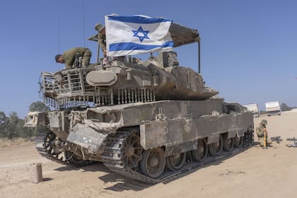 Un soldado israelí coloca una bandera israelí encima de un vehículo blindado de transporte de personal (APC) cerca de la frontera de Israel con Gaza, en el sur de Israel, el lunes 15 de abril de 2024.