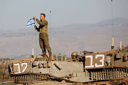 Un soldado israelí coloca una bandera nacional sobre un tanque Merkava durante un ejercicio militar cerca de la frontera con Líbano, en la región de la Alta Galilea, en el norte de Israel.