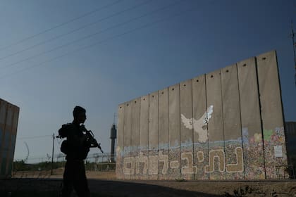 Un soldado israelí junto a un muro de seguridad con la frase "Camino a la paz" en el kibutz de Netiv Haasara