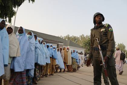 Un soldado junto a un grupo de niñas previamente secuestradas en su internado en el norte de Nigeria se ve el 2 de marzo de 2021 en la Casa de Gobierno en Gusau, estado de Zamfara, tras su liberación