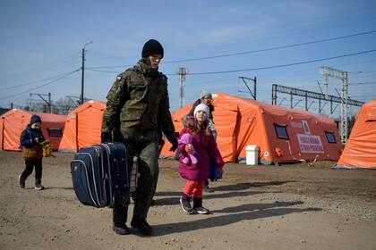 Un soldado polaco ayuda a una familia en su camino para tomar un tren en el cruce fronterizo de Medyka, después de cruzar la frontera entre Ucrania y Polonia, en el sureste de Polonia,