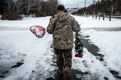 Un soldado ucraniano camina con las flores y un globo que compró para el Día de San Valentín en Kramatorsk